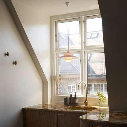 Suspension PH 5 Ø320 Opal rose pâle au-dessus d’un plan de travail