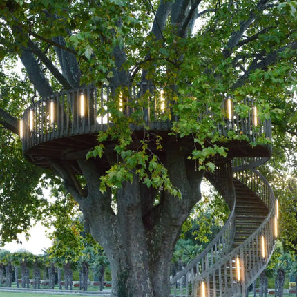 Appliques Elgar de Sammode le long de la rambarde et de l'escalier hélicoïdal d'une cabane perchée, à la tombée du jour