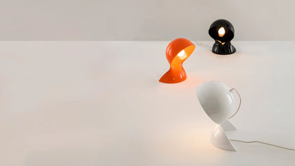 Trois lampes Dalù d’Artemide allumées, orange, noire et blanche