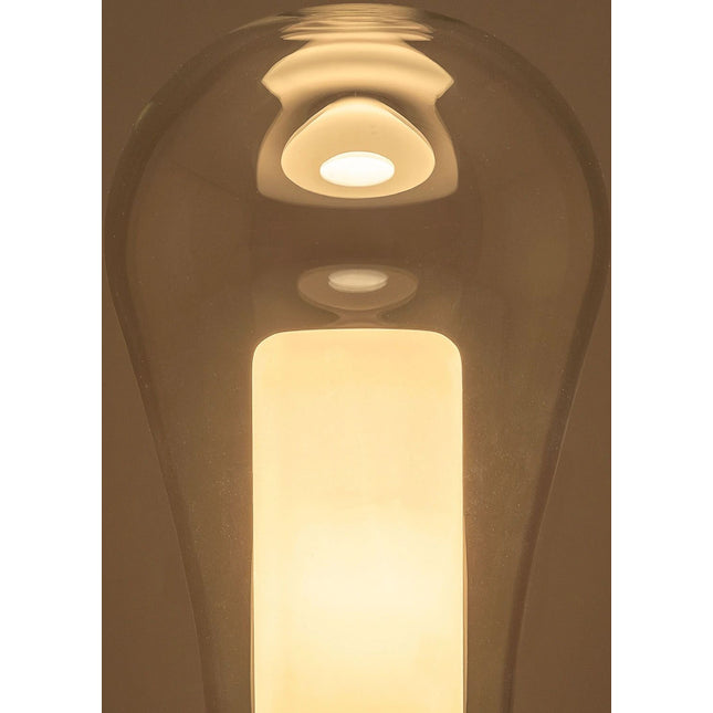 Détail de la lampe de table Metafisica Small de Produzione Privata allumée : bulle en verre soufflé transparent et diffuseur cylindrique