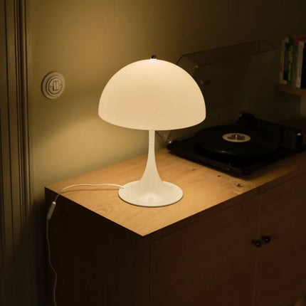 Panthella 320 blanche allumée sur une commode